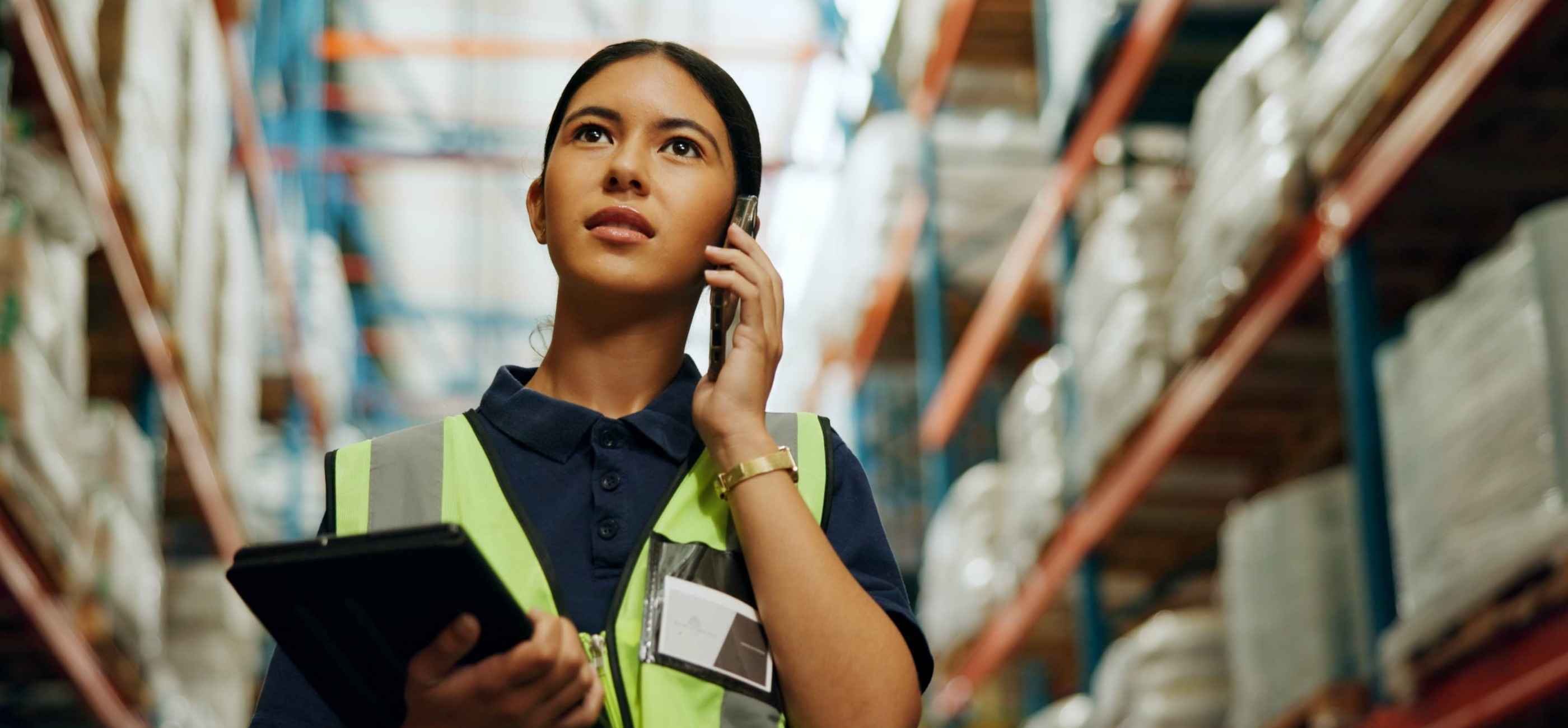 Kiwa ASI food safety auditor on the phone holding a tablet in a warehouse